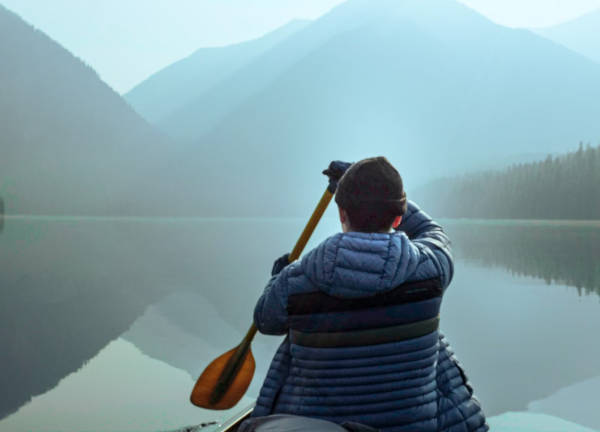 image of a person kayaking in a misty lake surrounded by mountains